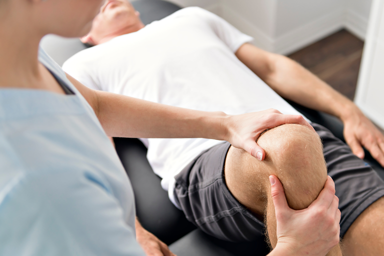 Physiotherapist treating a mans knee